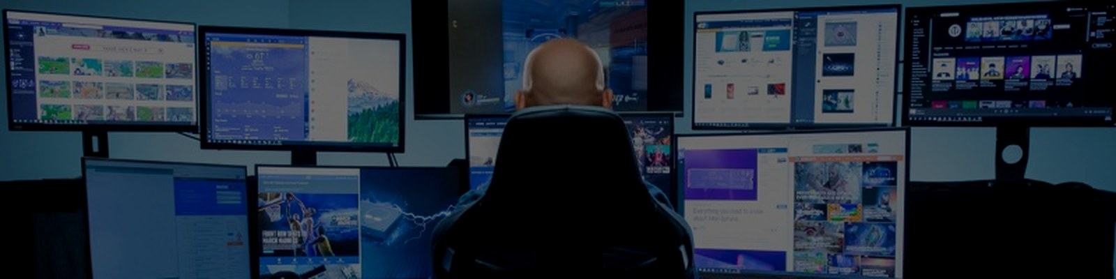 Operator at a darkened multi-monitor command desk